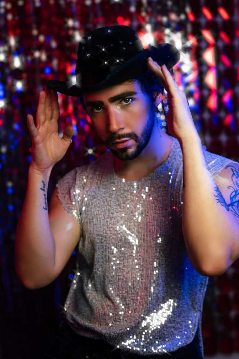 Person wearing a sparkly sequin outfit and black cowboy hat for a New Year's Eve party look