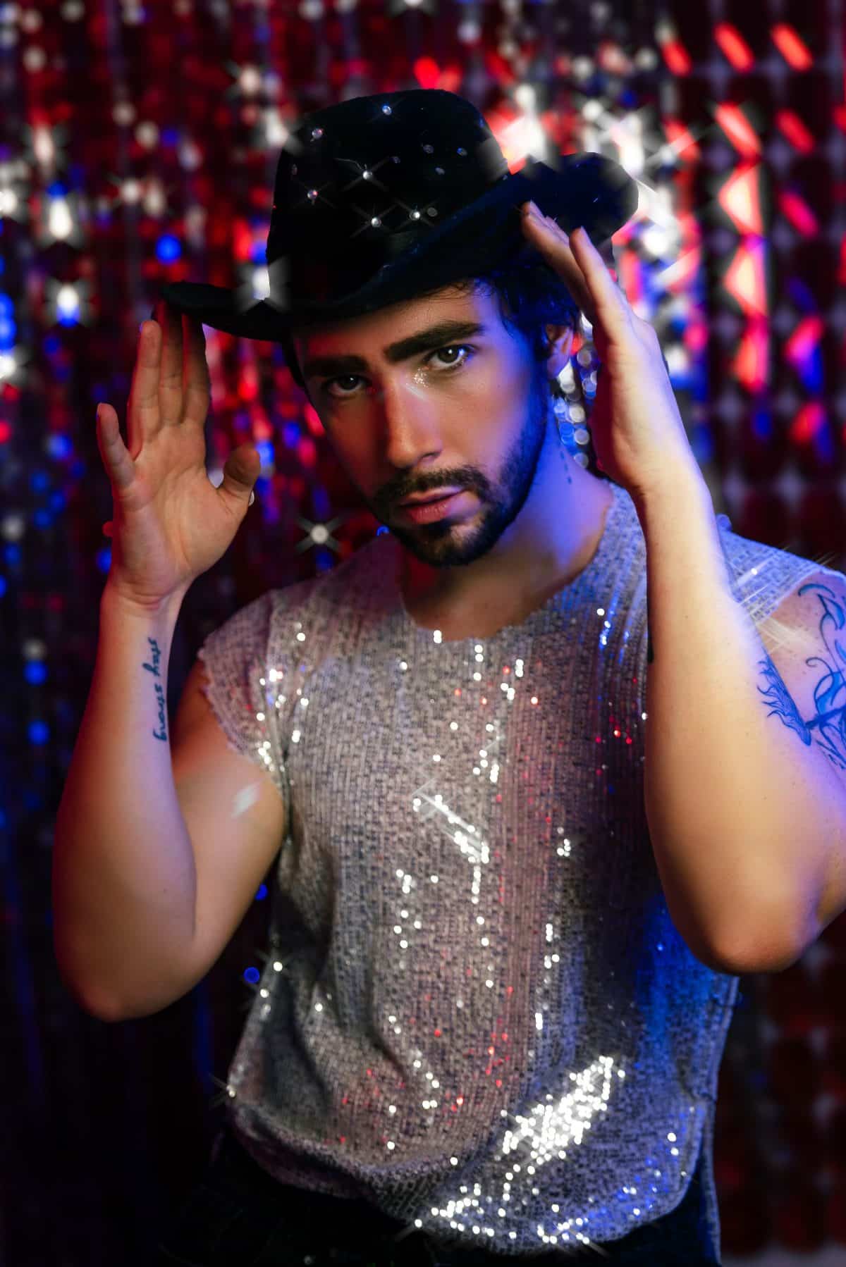 Person wearing a sparkly sequin outfit and black cowboy hat for a New Year's Eve party look