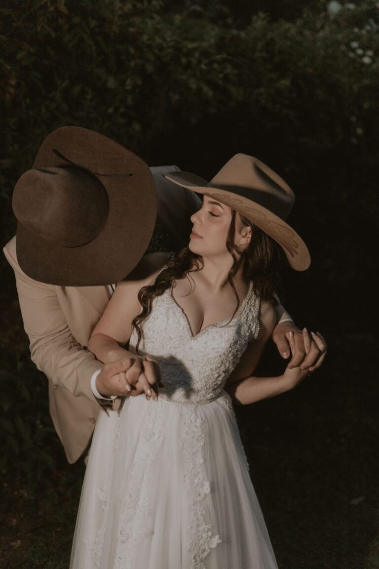 Couple wearing cowboy hats embracing outdoors, illustrating cowboy hat etiquette at outdoor events and weddings