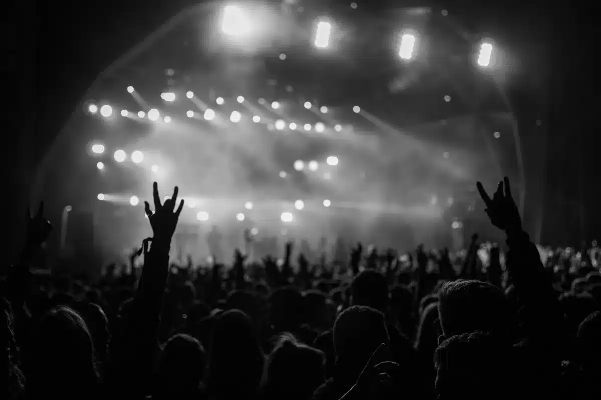 Silhouetted festival crowd under bright stage lights at night